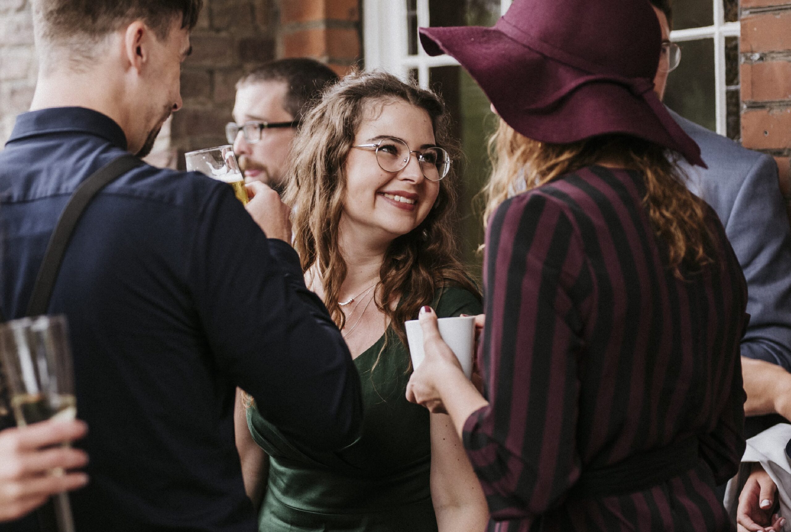 Menschen bei einer Außenveranstaltung, Frau in der Mitte lächelt, Getränke in der Hand.