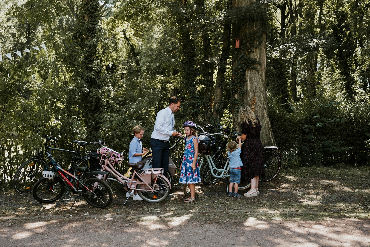 Familie am Waldrand mit Fahrrädern, Erwachsene und Kinder bereiten sich auf Ausfahrt vor.