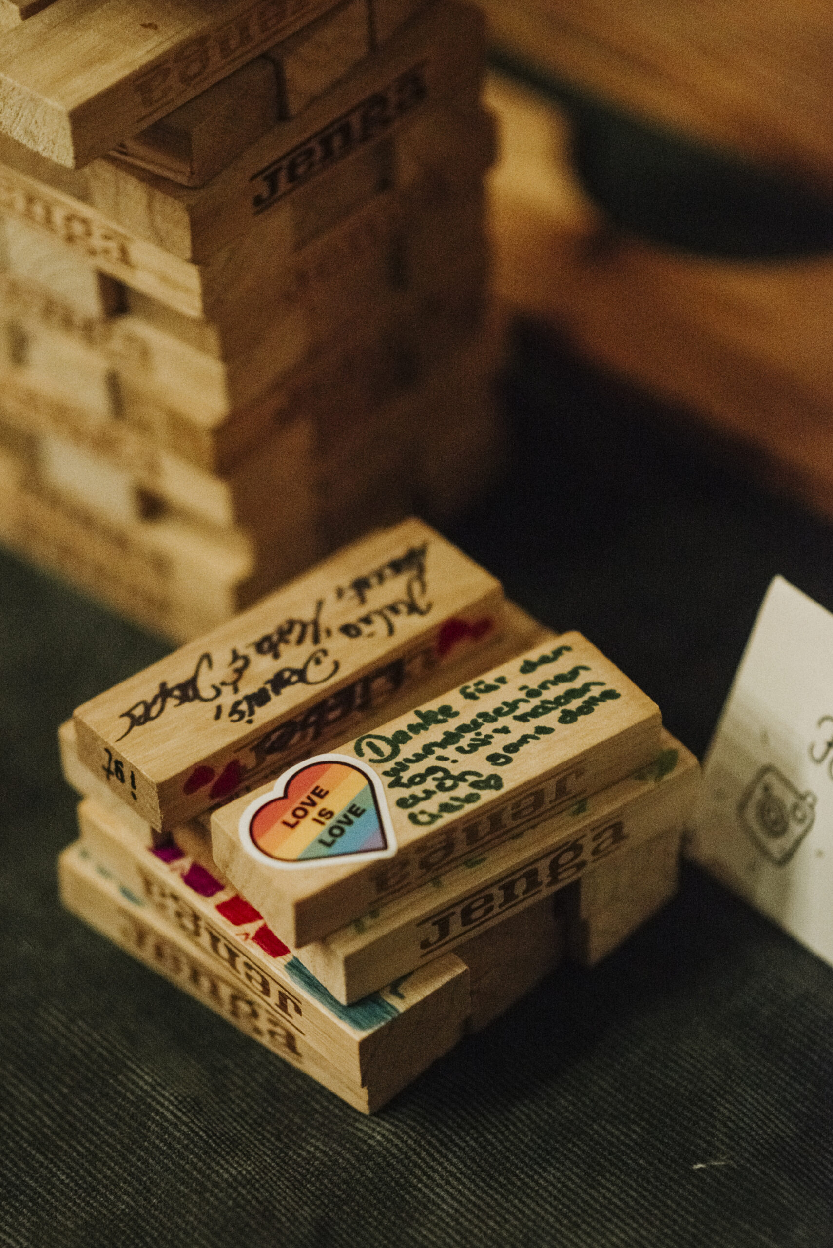 Ein Stapel Jenga-Steine mit handgeschriebenen Botschaften und einem "Love is Love" Aufkleber.