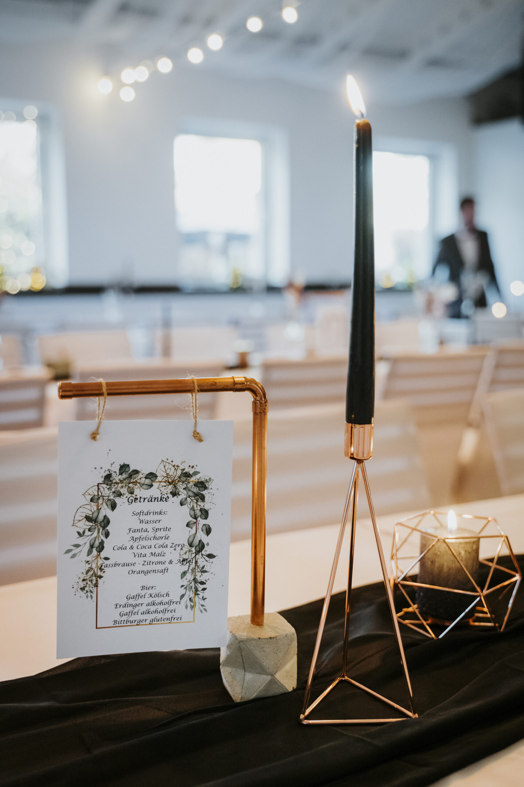 Stilvoll dekorierter Tisch mit brennender Kerze, Menükarte und festlicher Beleuchtung.