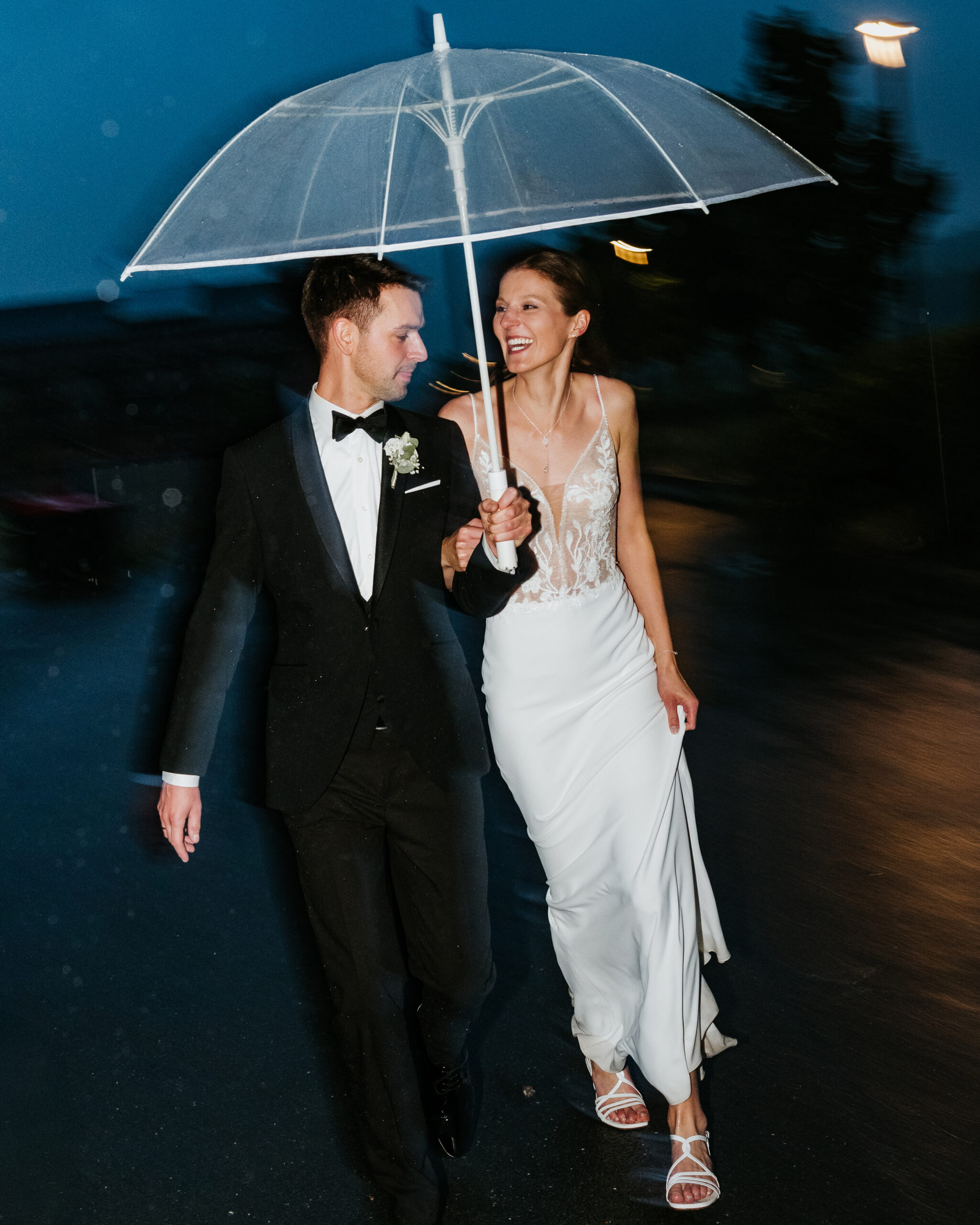 Hochzeitspaar rennt durch den Regen, fotografiert mit Blitzlicht am Abend