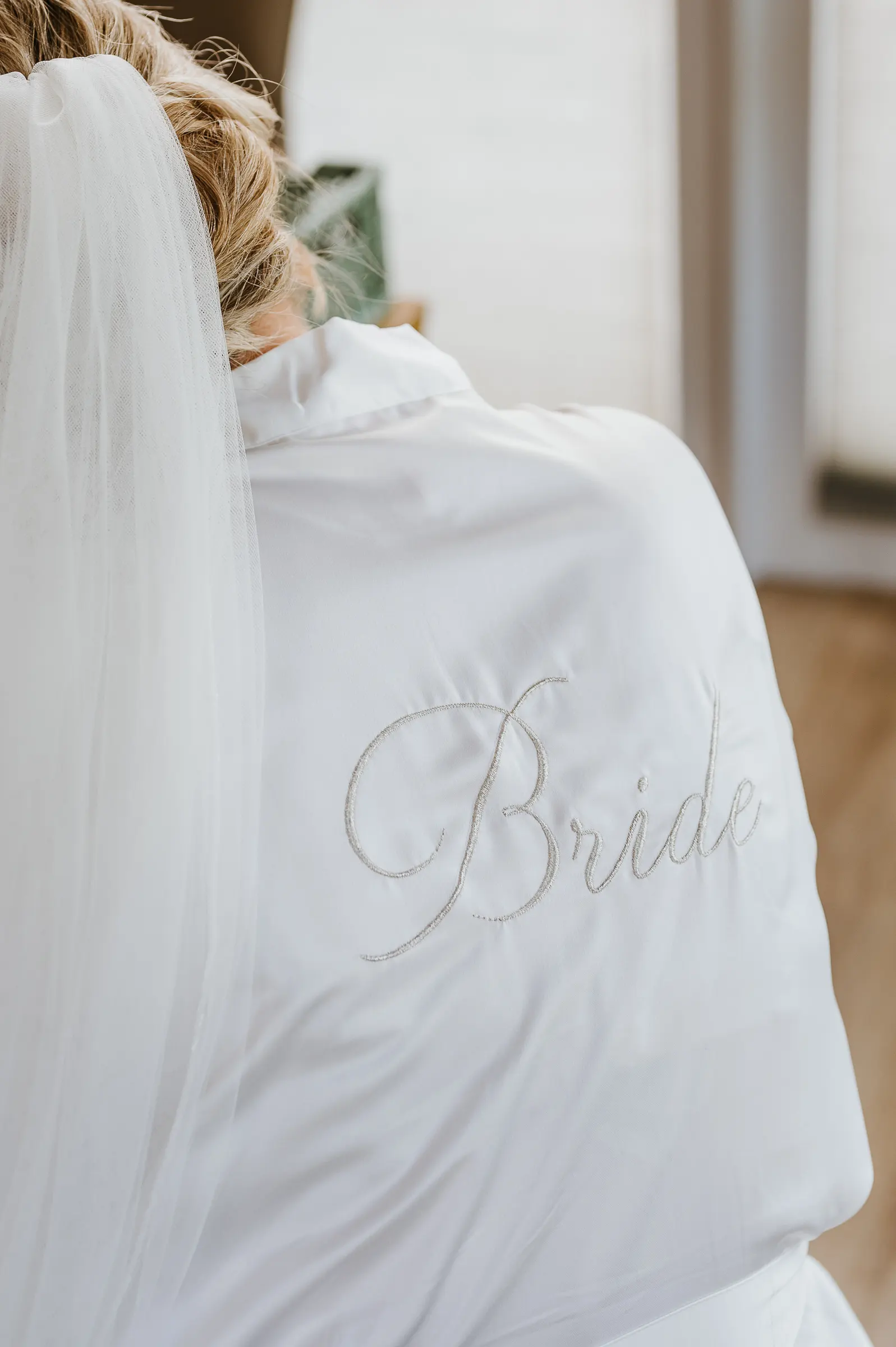 Nahaufnahme einer Braut von hinten mit Schleier, besticktem weißen Hochzeitskleid.